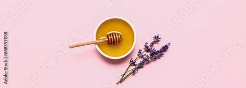 Bowl of sweet lavender honey, dipper and flowers on pink background, top view photo