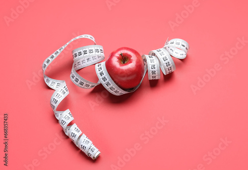 Apple and measuring tape on red background. Diet concept