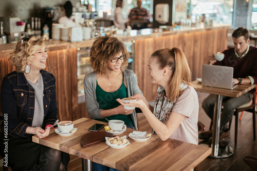Three young multiracial women having coffee in a cafe