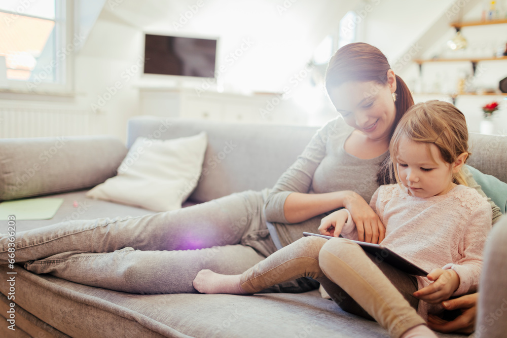 Young mother and daughter using the tablet at home Young mother and daughter using the tablet at home