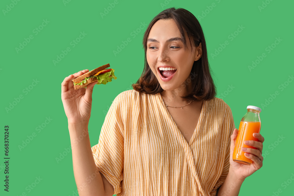 Beautiful young woman with tasty sandwich and orange juice on green background Beautiful young woman with tasty sandwich and orange juice on green background