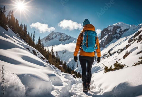 Female backpacker with backpack dressed warm down jacket enjoying snowy mountains landscape while she trekking winter mountain forest route. Active people in the nature concept image. photo