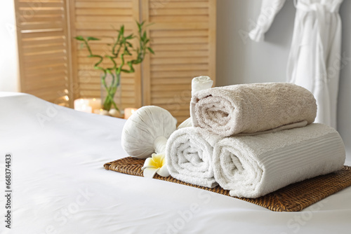 Towels with flower and herbal bags on couch in spa salon, closeup