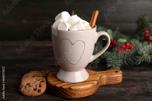 Cup of tasty Christmas cocoa with marshmallows, cinnamon and cookies on wooden background