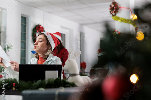 Фотография Tired unhappy employee overwhelmed by stressful difficult paperwork in xmas decorated office