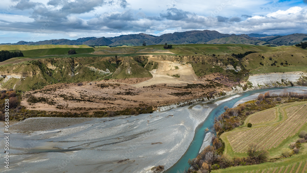 The blue water of the Awatere river flowing through agricultural farmland in a rural valley