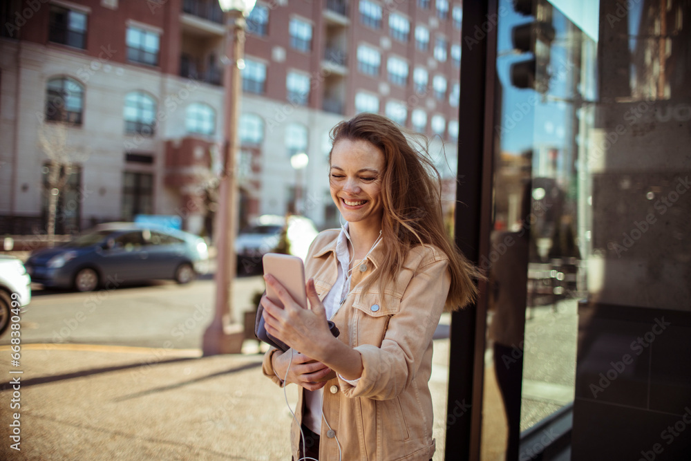 Young beautiful woman walking in the city and using a smartphone