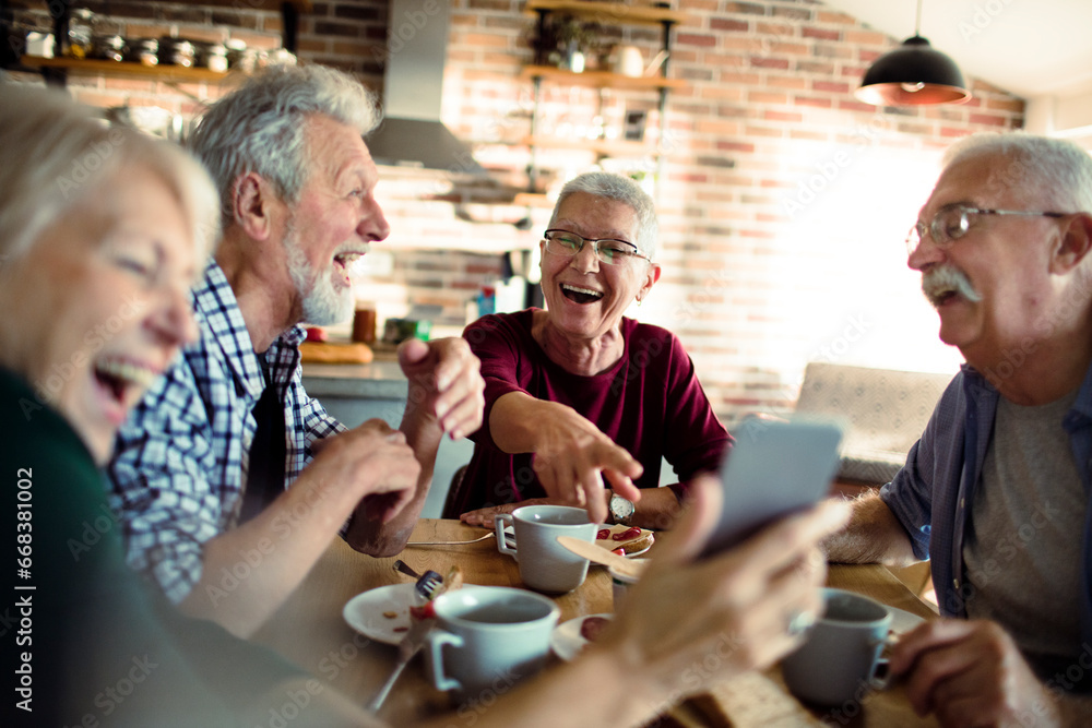 Four senior people using a smartphone and laughing