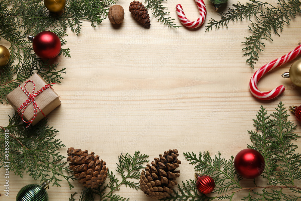 Frame made of Christmas branches, decor and gift on light wooden background Frame made of Christmas branches, decor and gift on light wooden background