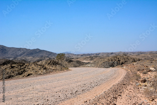 A deserted stony road in the hot desert foothills under a bright blue sky