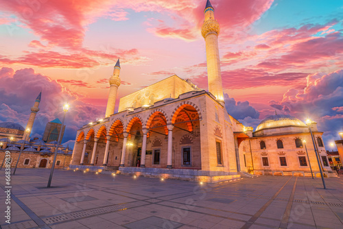 Selimiye Mosque in Konya, Turkey, bathes in the warm hues of sunset, its elegant domes and minarets silhouetted against the fading sky. The tranquil atmosphere deepens as the evening prayer begins photo