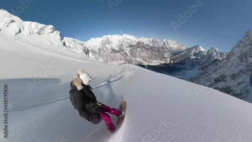 SELFIE: Active lady sprays fresh snow while snowboarding down the snowy mountain on an adventure trip in beautiful Albanian Alps. She enjoys riding steep untouched terrains between snowed highlands. photo