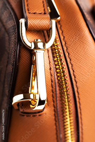 Metal gold-plated carabiner and ring-strap on a fashionable women's handbag. Accessory for a woman's look. Close-up.