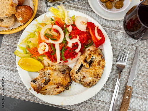 Hake fish fillets fryed granished with vegetable salat and lemon. Hake fillet in Spanish style. photo