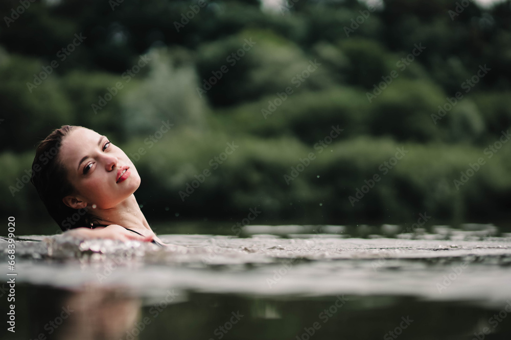 beautiful woman swims in the water of a lake river, swimming lessons.