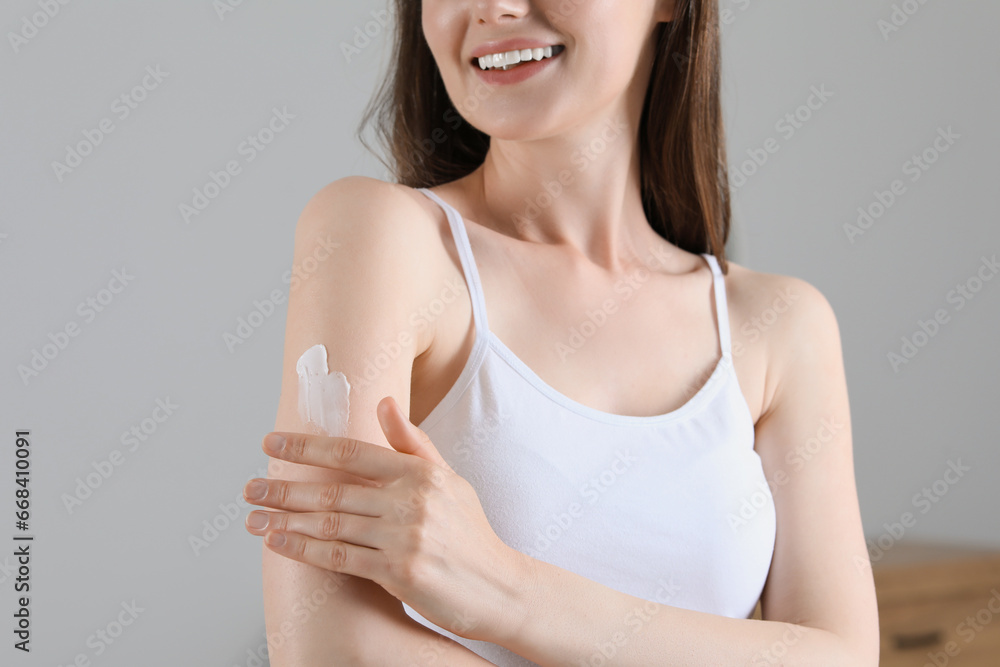 Woman applying body cream onto arm indoors, closeup. Space for text Woman applying body cream onto arm indoors, closeup. Space for text