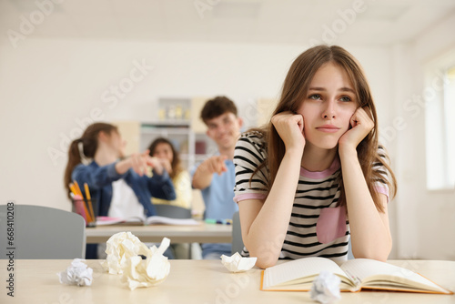 Teen problems. Students pointing at upset girl in classroom, selective focus