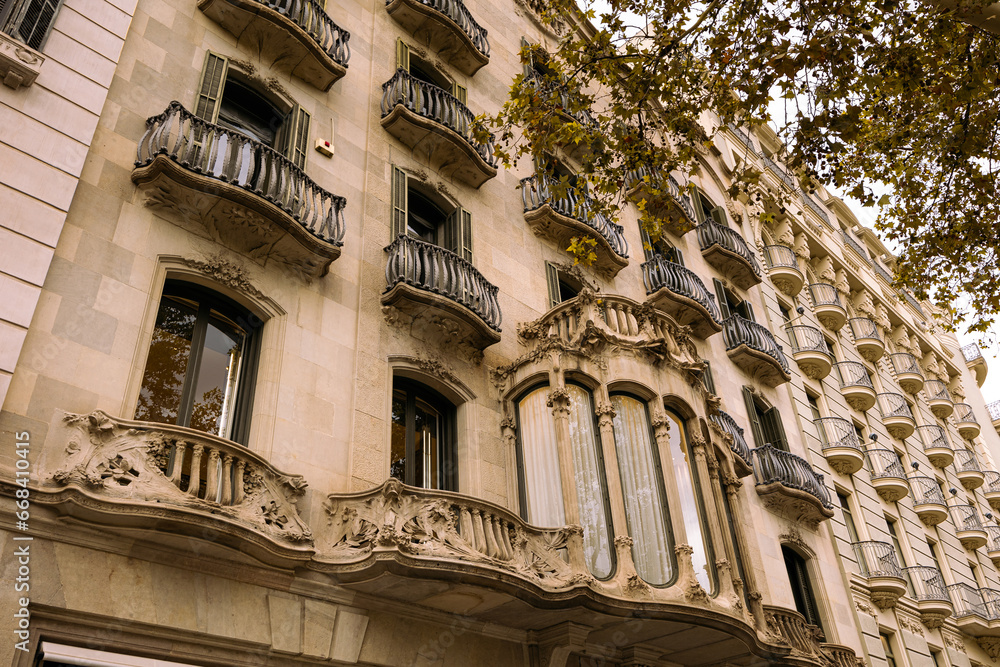 Unique facades of ancient buildings along Passage de Gracia Street, decorated with columns, statues, with carved balcony railings. Details of authentic buildings located on main avenue of Barcelona