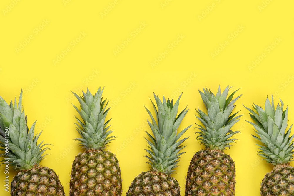 Fototapeta premium Whole ripe pineapples on yellow background, flat lay. Space for text