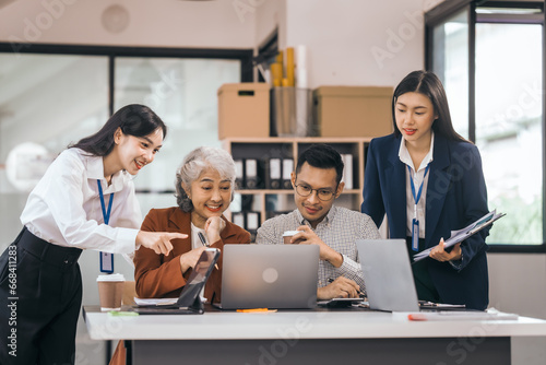 Four asian people in an office  working together on laptops  discussing tasks. annual gathering where attendees share and discuss opinions  presentation teamwork group meeting laptop in boardroom