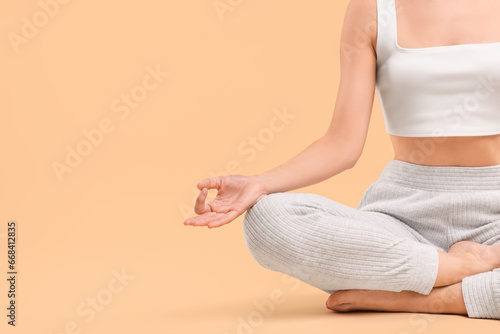 Woman practicing yoga on beige background, closeup and space for text. Lotus pose