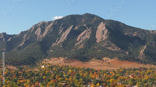 Aerial up close view of Flatiron mountains in Boulder Colorado surrounded by peak fall colors of green, red, and yellow trees photo