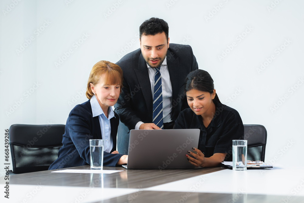 Group of three professional discussing numbers in a business meeting with use laptop. Team of business people brainstorming solutions for a project as they work towards the success of their company. Group of three professional discussing numbers in a business meeting with use laptop. Team of business people brainstorming solutions for a project as they work towards the success of their company.