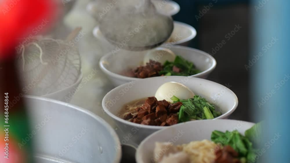 Preparing chicken noodles. View of a penjual mie ayam bakso or meatball chicken noodle seller who is making chicken noodles for the buyer. Selective focus Preparing chicken noodles. View of a penjual mie ayam bakso or meatball chicken noodle seller who is making chicken noodles for the buyer. Selective focus