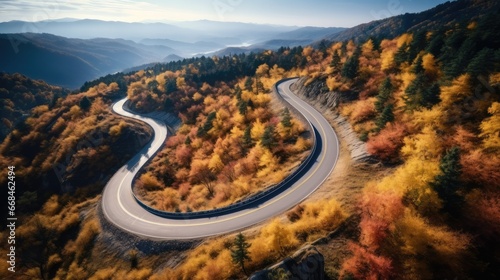 Aerial view over winding road on a mountain top with trees by autumn. © visoot