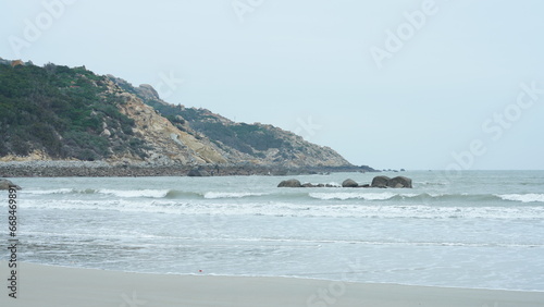The ocean beach view with the rock shore and tide waves