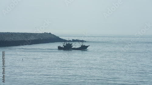 The peaceful sea view with the fishing boat sailing on it in the cloudy day © Bo