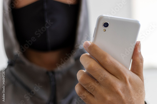 Obraz na płótnie スマートフォンを持つ、顔を隠した怪しい男性