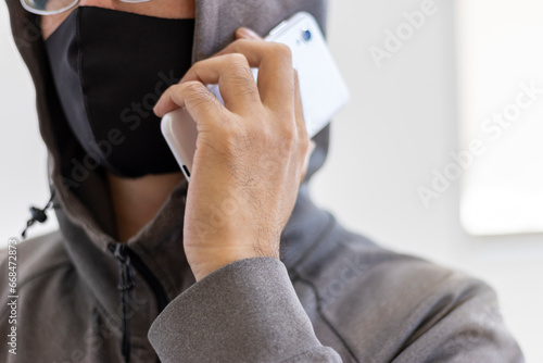 スマートフォンで電話をする顔を隠した怪しい男性