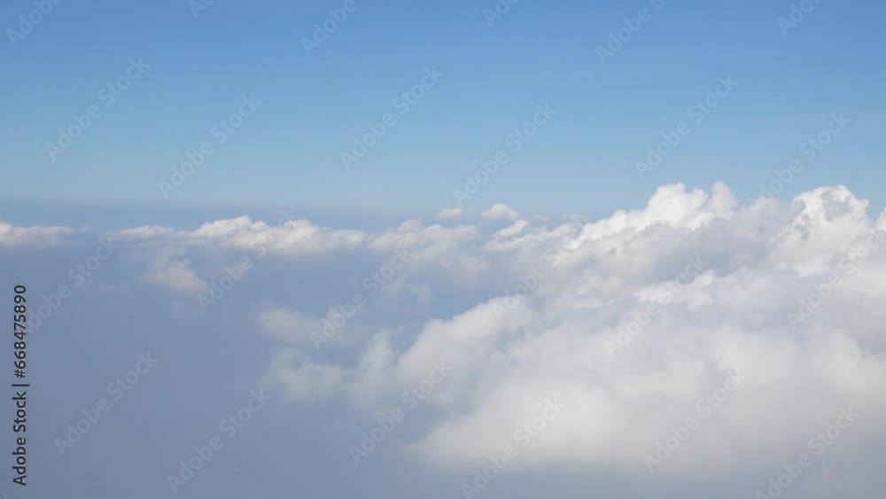 Aerial view of puffy white cloud over clear blue sky while flying in airplane, Airplane flight flying above the clouds. View from the window of the plane traveling by air Aerial view of puffy white cloud over clear blue sky while flying in airplane, Airplane flight flying above the clouds. View from the window of the plane traveling by air