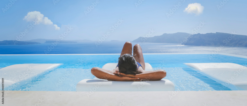 Young Asian women on vacation at Santorini relaxing in swimming pool looking out over Caldera ocean - obrazy, fototapety, plakaty 