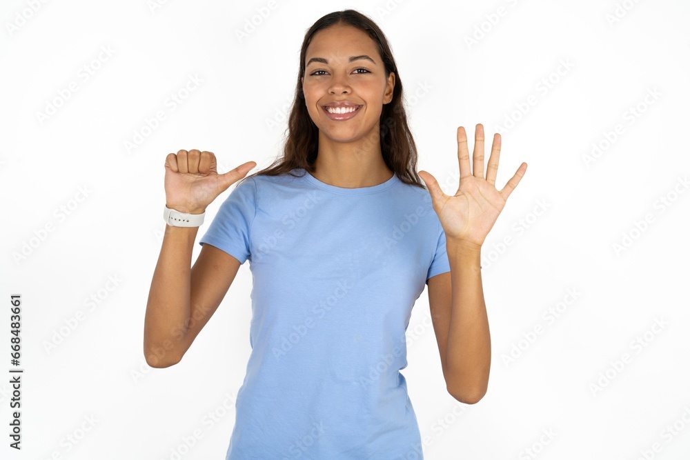 Beautiful girl wearing blue T-shirt showing and pointing up with fingers number six while smiling confident and happy. Beautiful girl wearing blue T-shirt showing and pointing up with fingers number six while smiling confident and happy.