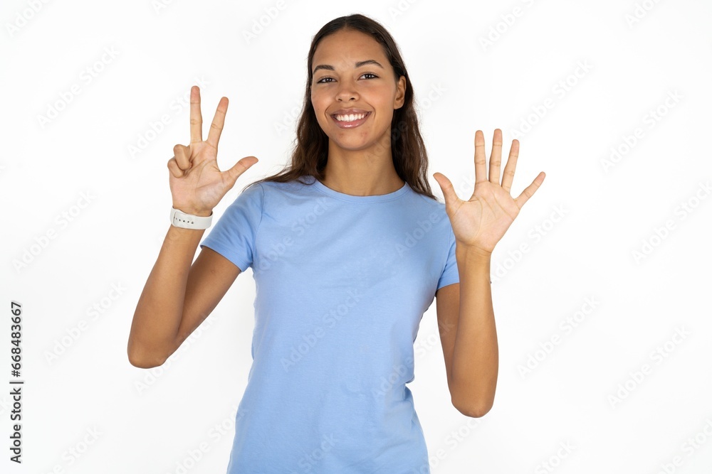 Beautiful girl wearing blue T-shirt showing and pointing up with fingers number eight while smiling confident and happy. Beautiful girl wearing blue T-shirt showing and pointing up with fingers number eight while smiling confident and happy.