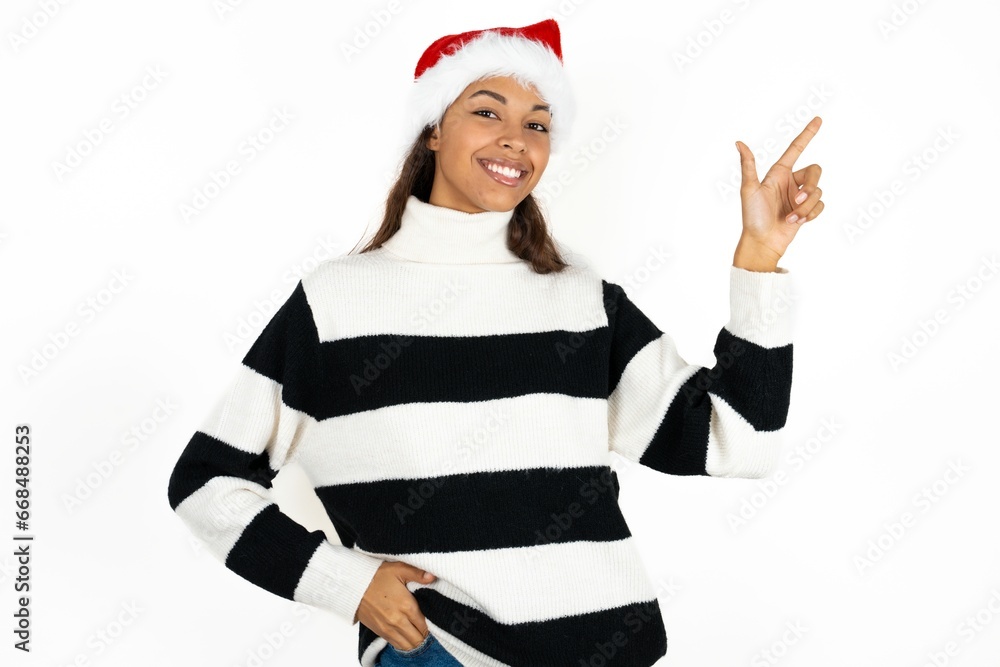 Beautiful woman wearing christmas hat looking at camera indicating finger empty space sales Beautiful woman wearing christmas hat looking at camera indicating finger empty space sales