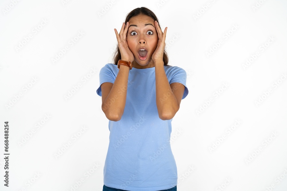 young beautiful woman with scared expression, keeps hands on head, jaw dropped, has terrific expression. Omg concept young beautiful woman with scared expression, keeps hands on head, jaw dropped, has terrific expression. Omg concept