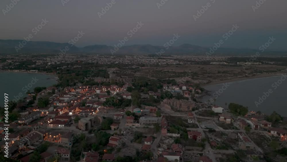 Aerial view over illuminated Side old town Mediterranean neighbourhood towards the Taurus mountain range at sunset Aerial view over illuminated Side old town Mediterranean neighbourhood towards the Taurus mountain range at sunset