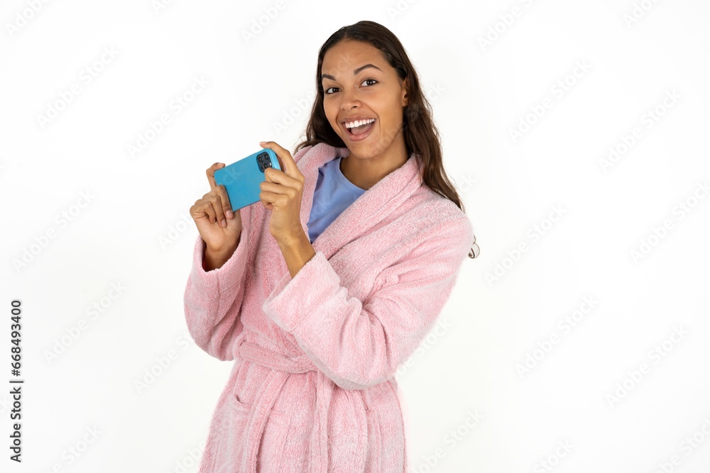 Nice addicted cheerful Young beautiful woman wearing pink bathrobe using gadget playing network game Nice addicted cheerful Young beautiful woman wearing pink bathrobe using gadget playing network game