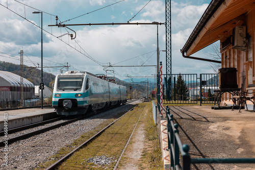 Older type of high speed train is rushing through the station of Sentjur in Slovenia on a summer day. Old and neglected train tracks but nice station.