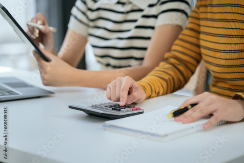 Business team using a calculator to calculate the numbers of statistic business profits growth rate on documents graph data  desk in the office.