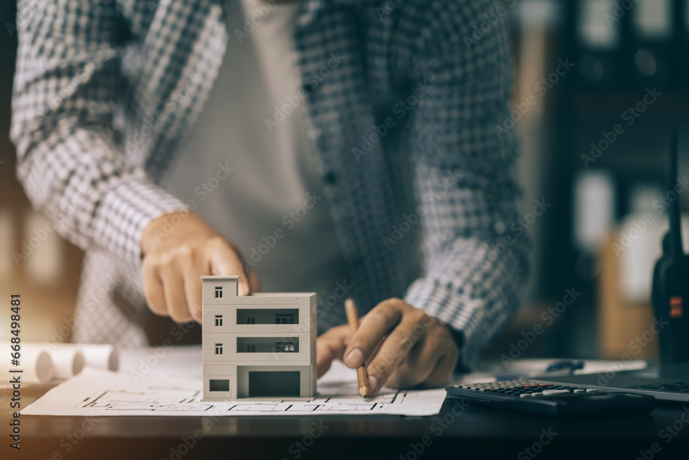 Fototapeta premium Close up of male architect hands making model house. Man architect working in the office.
