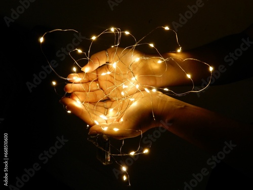 Hands of a woman holding Christmas lights in the dark