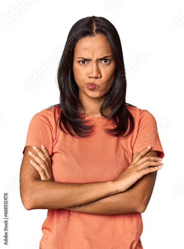 Young Filipina with long black hair in studio frowning face in displeasure, keeps arms folded. © Asier