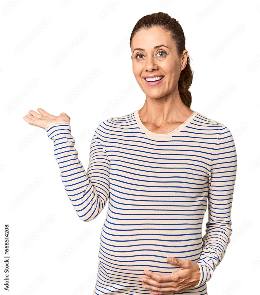 Pregnant middle-aged woman in studio setting showing a copy space on a palm and holding another hand on waist. Pregnant middle-aged woman in studio setting showing a copy space on a palm and holding another hand on waist.