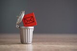 Closeup image of wooden cube with mail icon inside trash can. Junk mail and spam mail concept.