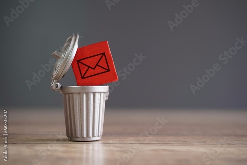 Closeup image of wooden cube with mail icon inside trash can. Junk mail and spam mail concept.
