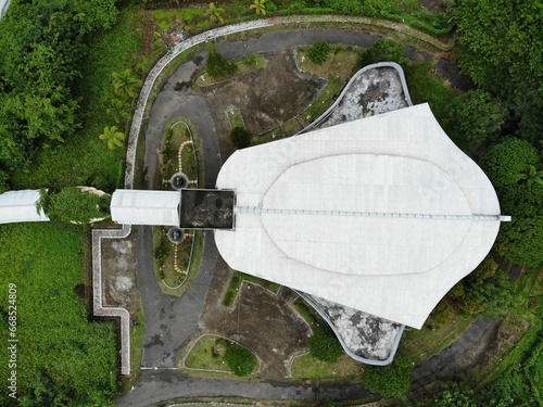 A top down aerial view of building shaped like a manta ray called Gedung Pari, surrounded by green trees in Waisai, Raja Ampat, West Papua, Indonesia.  photo